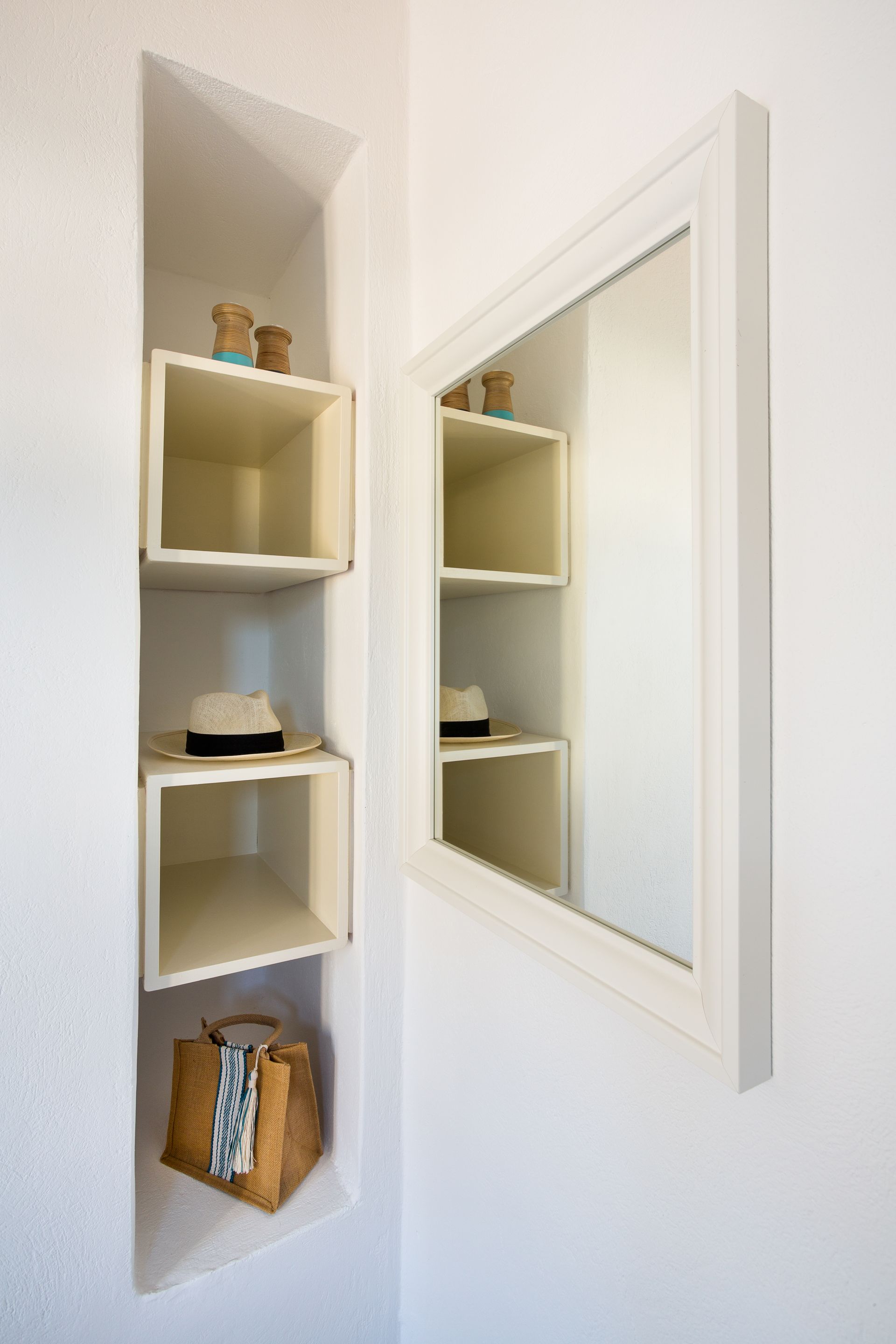 A corner of a room with shelves and a mirror