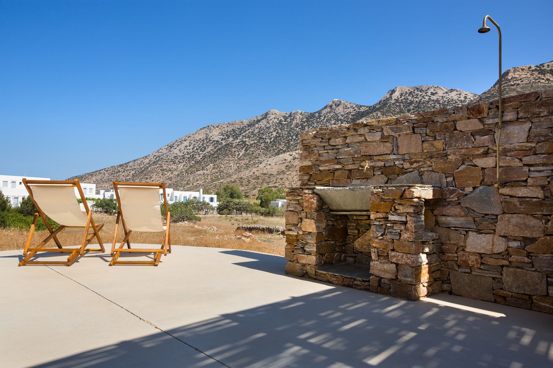 Two chairs are sitting in front of a stone wall with mountains in the background.
