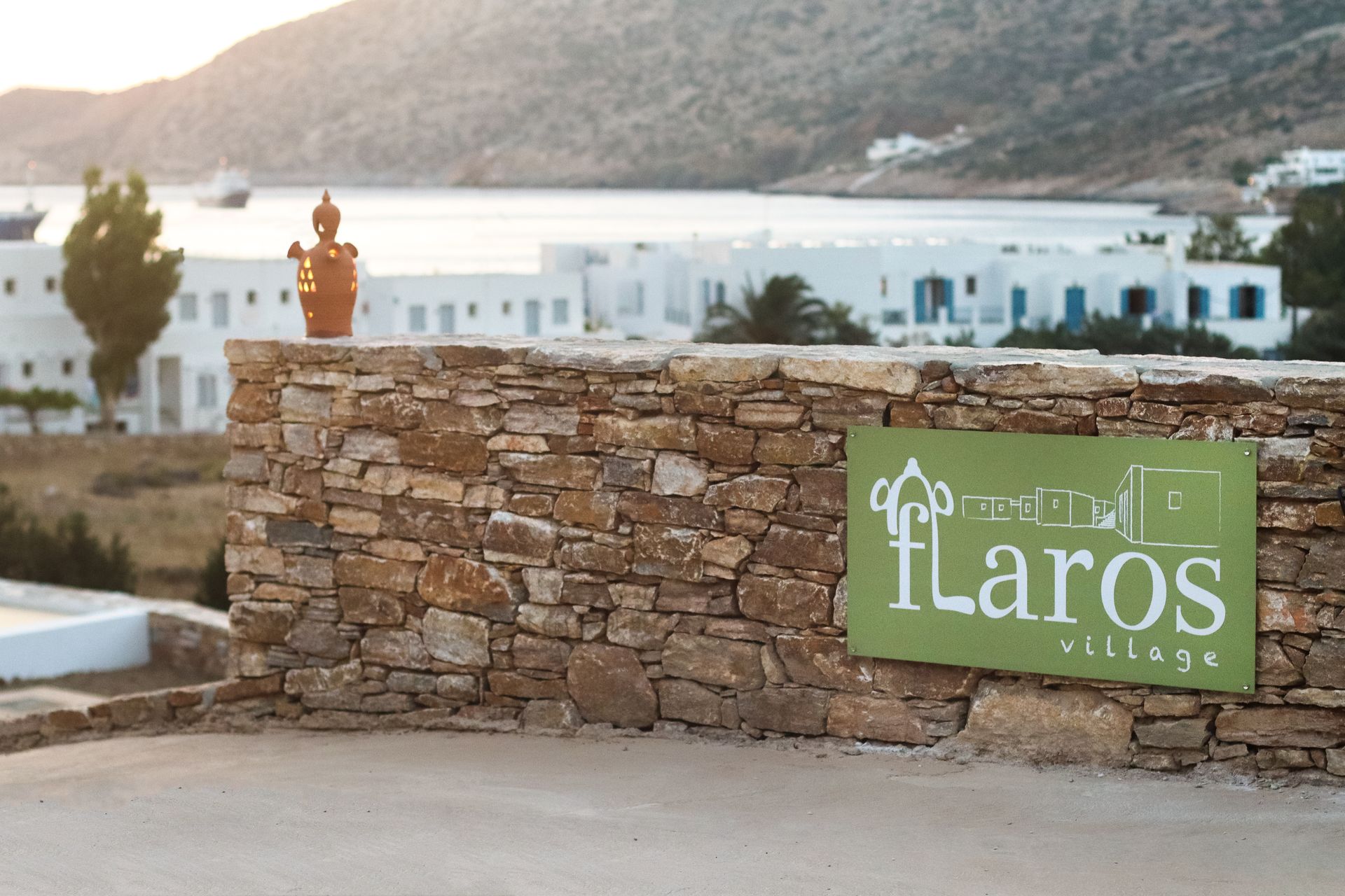A sign on a stone wall says flaros village