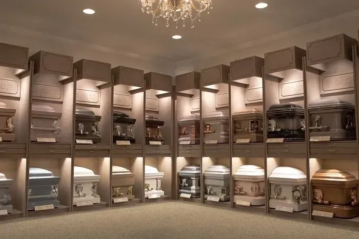 A showroom displaying a wide selection of various colored and metallic caskets arranged on shelves in a well-lit room.