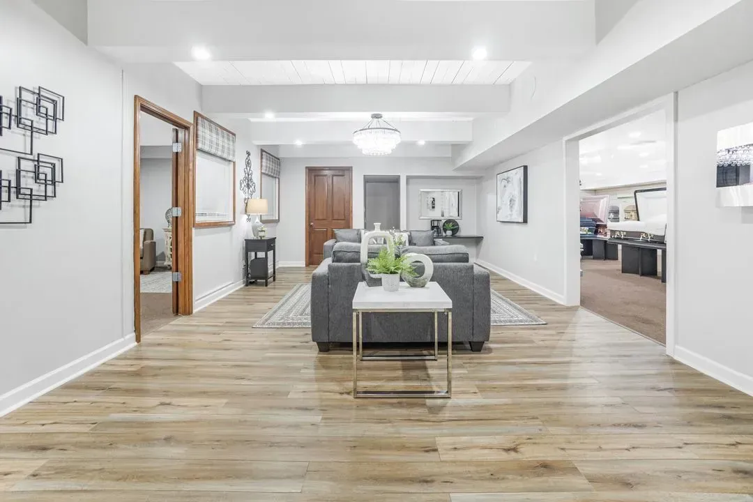 Modern space with light wood flooring, white walls, and a gray sofa facing a small side table in the center.