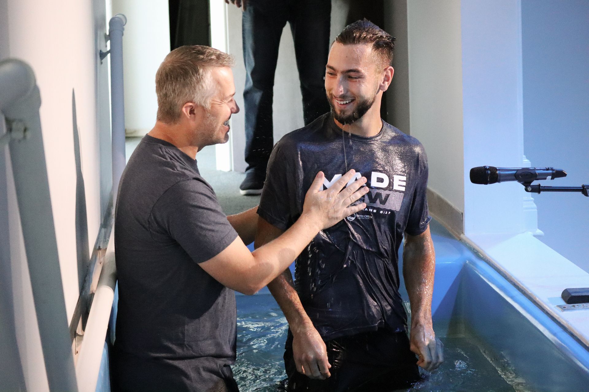 Two men are standing next to each other in a pool of water.