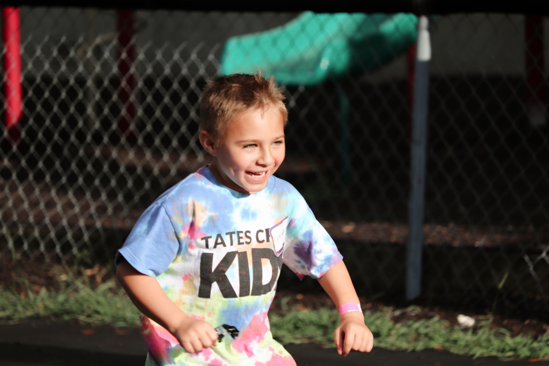 A young boy wearing a tie dye shirt that says states of kid