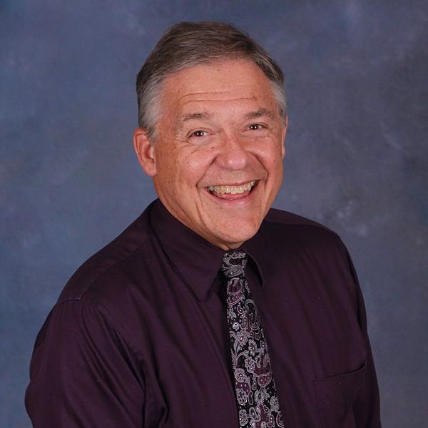 A man in a blue plaid shirt is smiling for the camera.