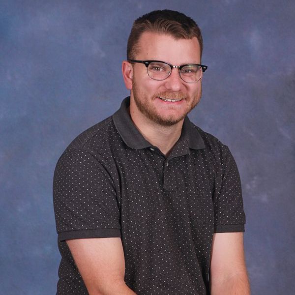 A man with glasses and a beard is wearing a white hoodie