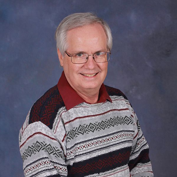 A man in a blue plaid shirt is smiling for the camera.