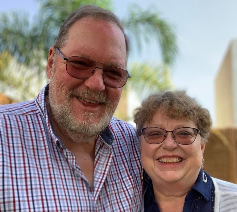 A man and a woman are posing for a picture and smiling for the camera.