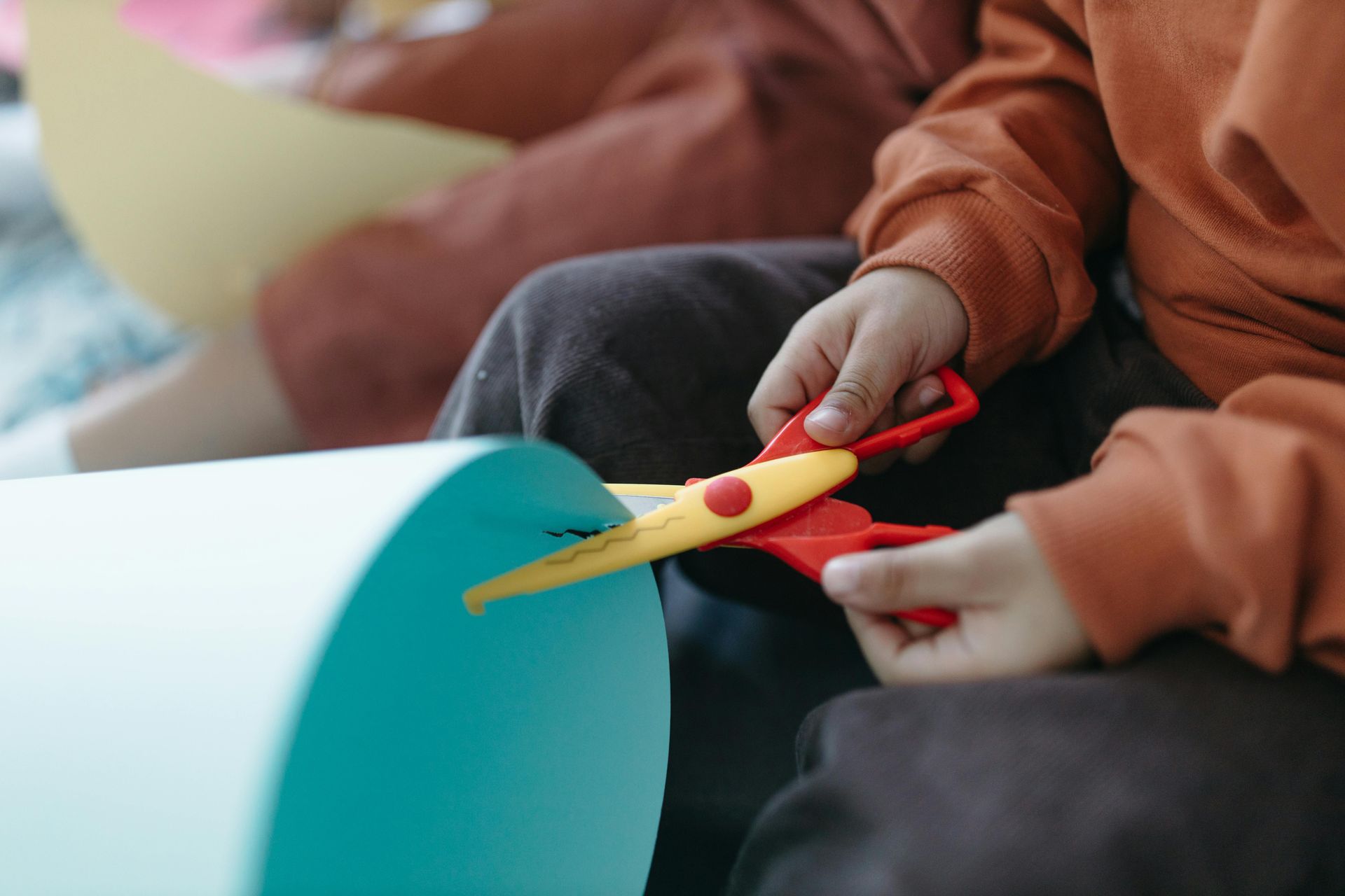 A child is cutting a piece of paper with scissors.