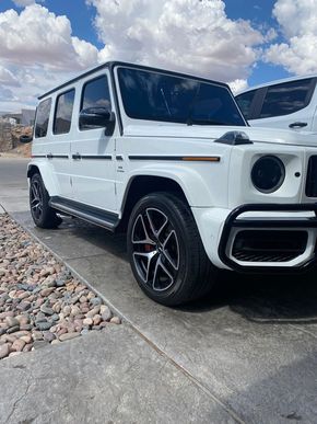 White Mercedes G-Class SUV parked on a driveway under a cloudy sky