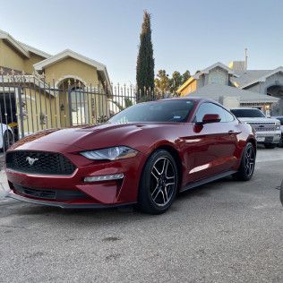 Red Ford Mustang parked on a residential street at dusk