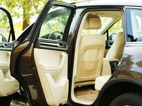 Open car door revealing beige leather interior and rear seat in a parked car