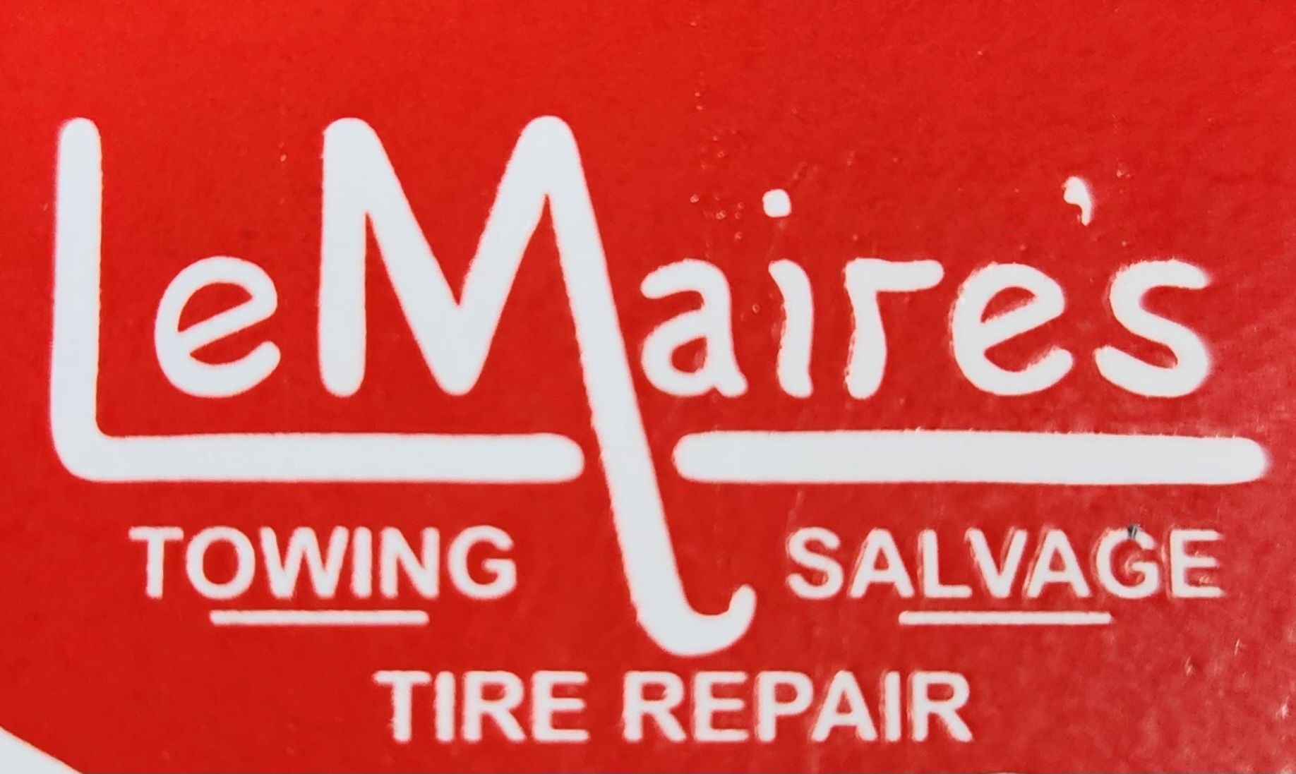 Logo for LeMaire's Towing: red tow truck with a raised crane, on a navy blue shield;