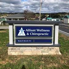 A sign for alliant wellness & chiropractic is sitting in the grass.