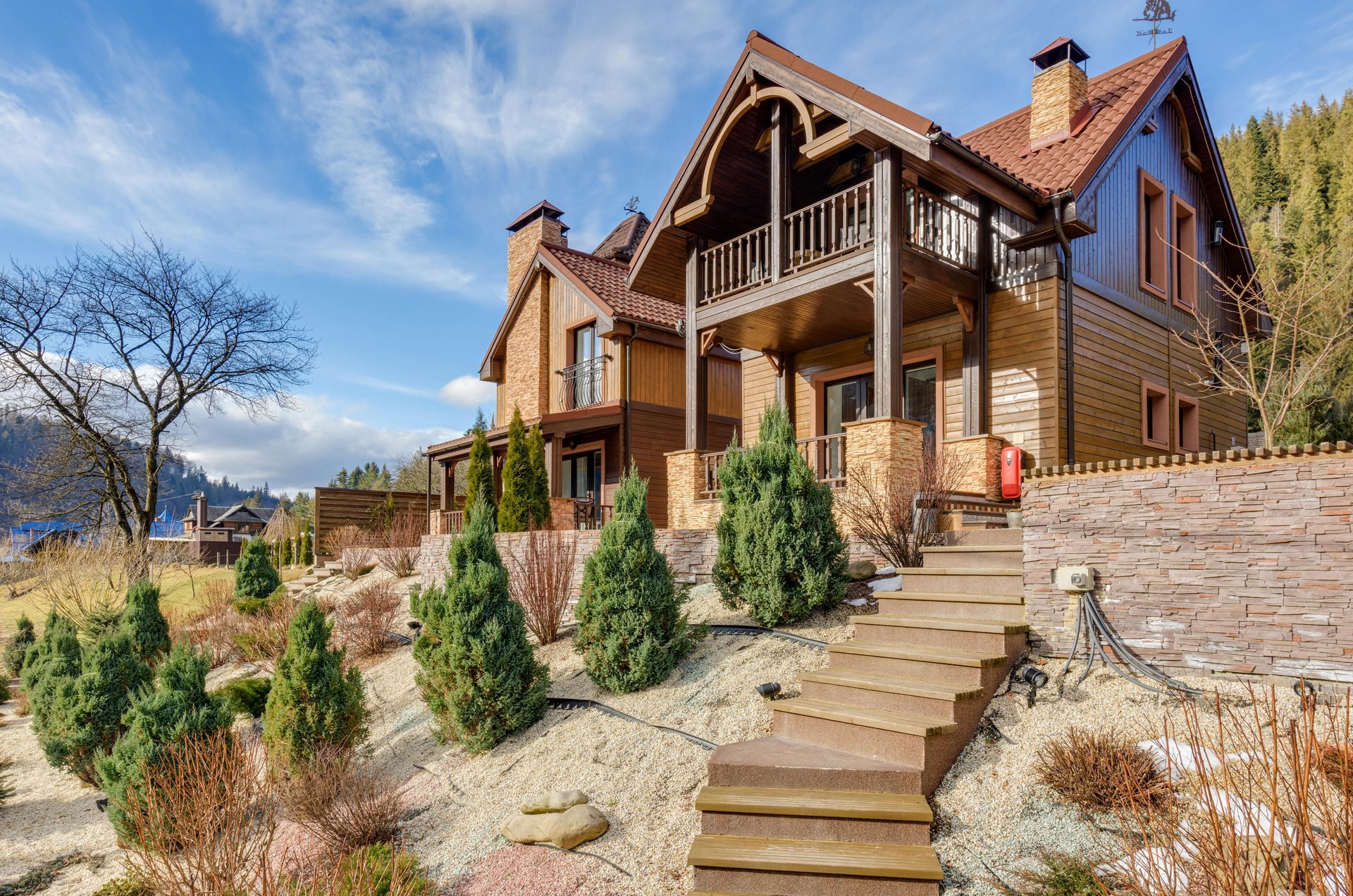 Two-story brick house with a balcony and steps leading up from a landscaped yard.