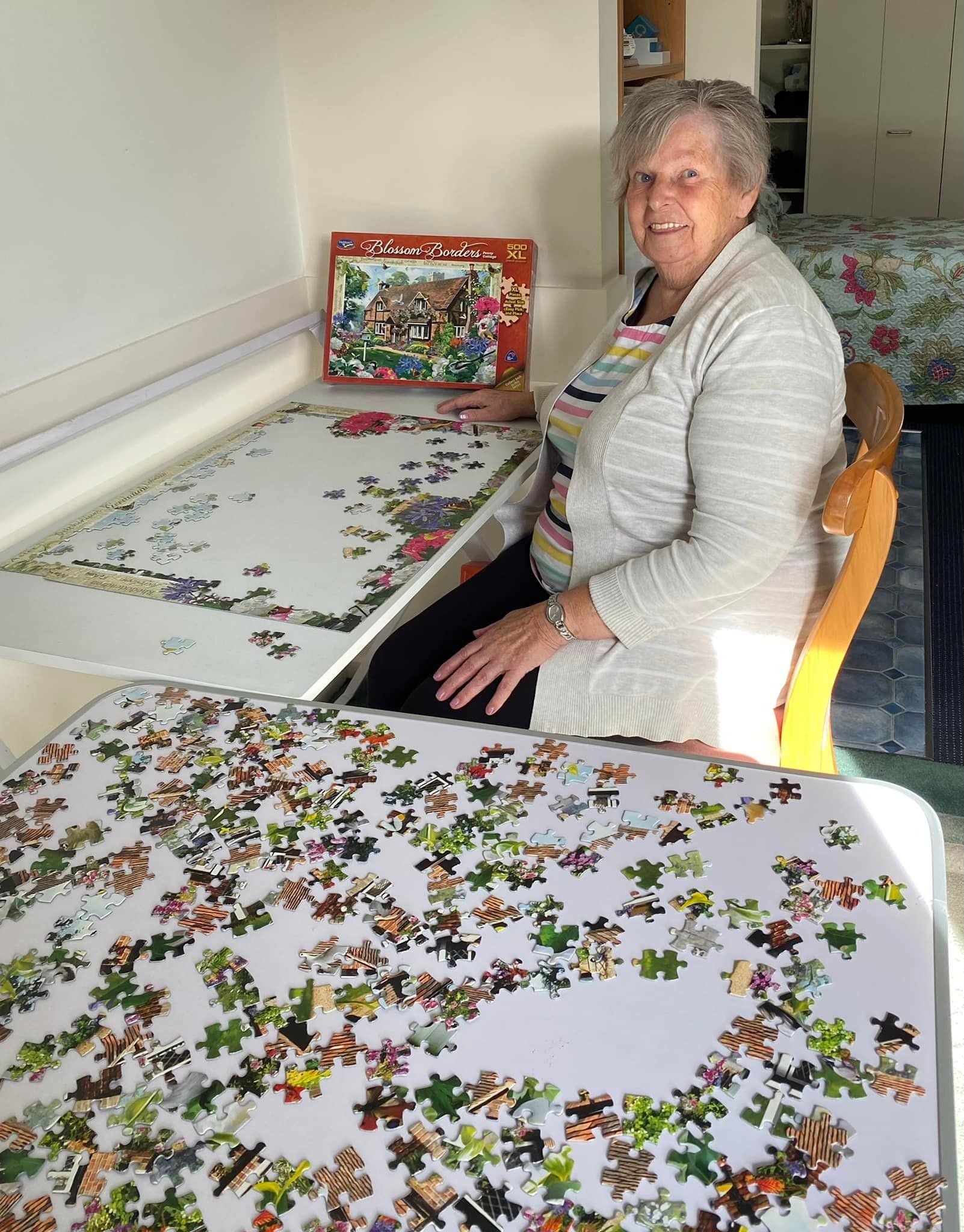 A woman is sitting at a table with a box of puzzles on it