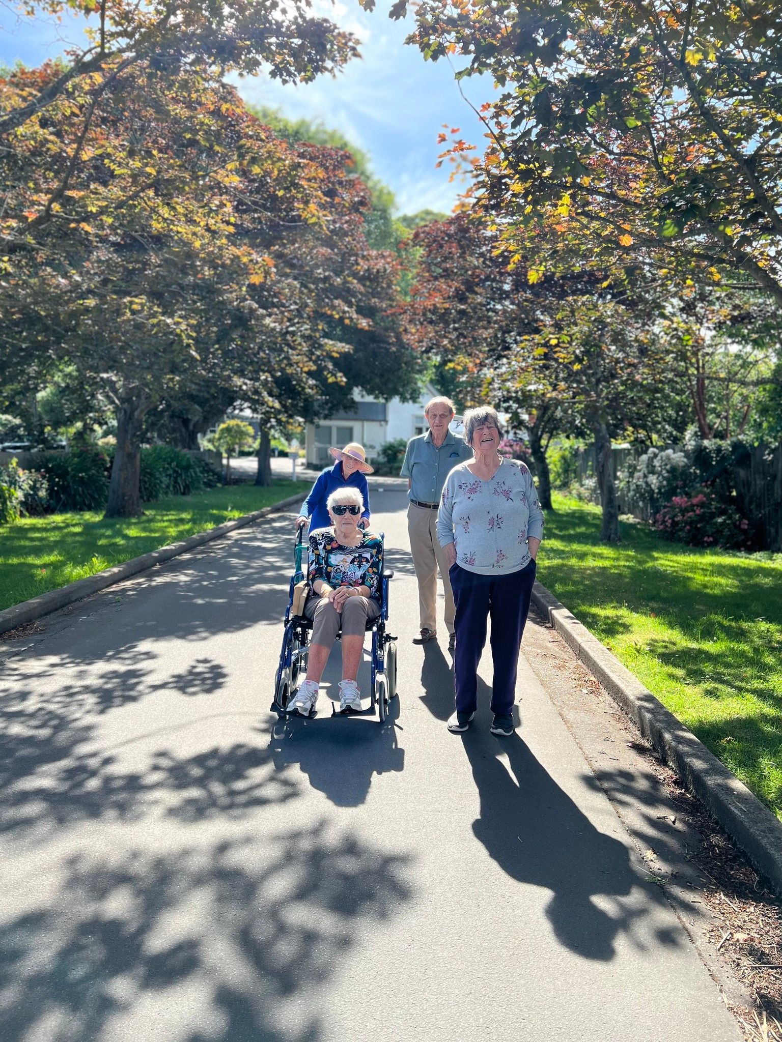 A group of people are walking down a street with a woman in a wheelchair.