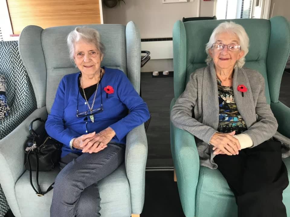 Two older women are sitting next to each other in chairs.