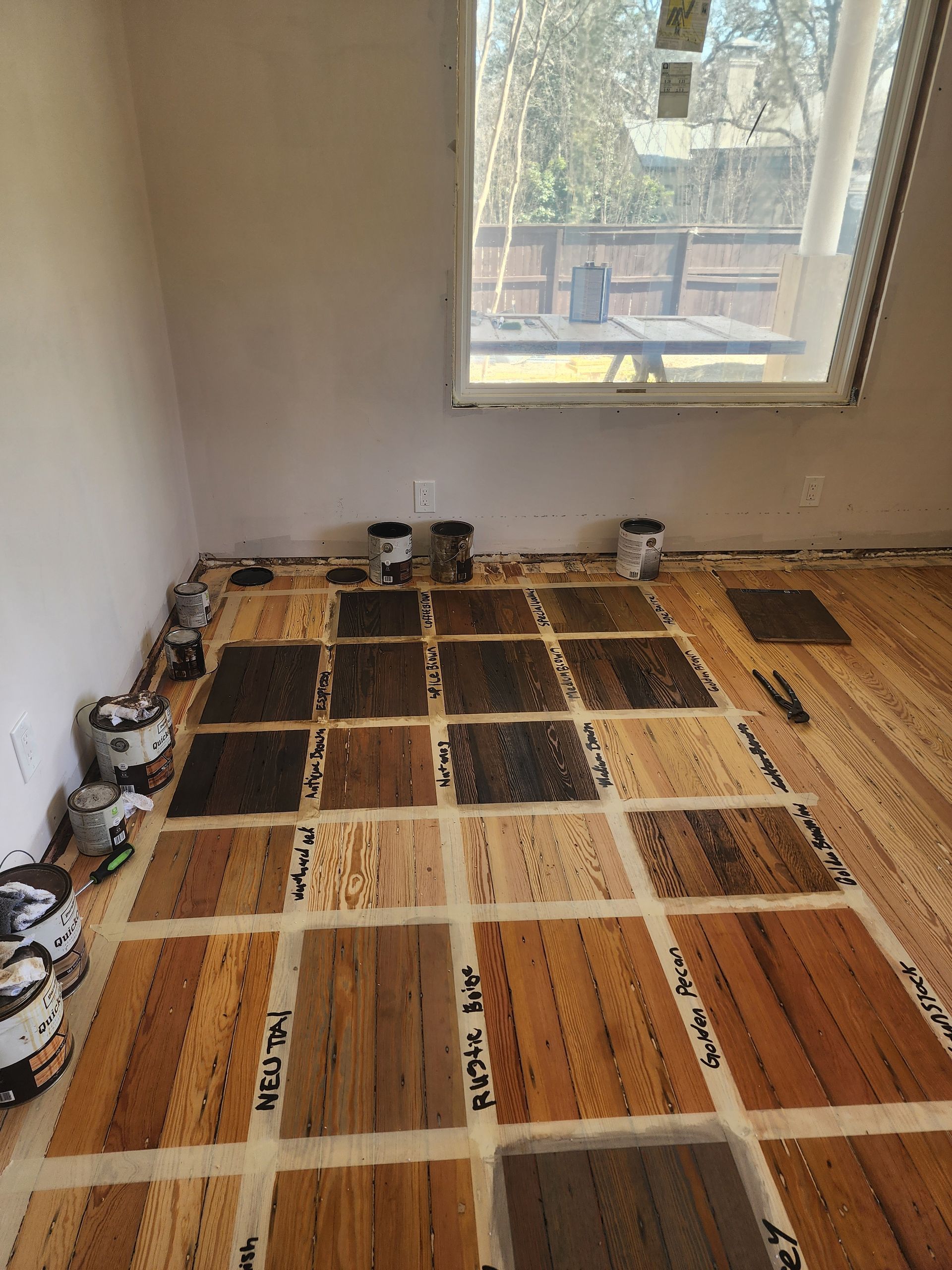 Small room with hardwood flooring under construction, covered in taped protective paper near a window.