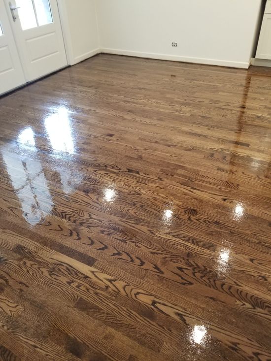 Glossy hardwood floor in an empty room with white walls and a closed door