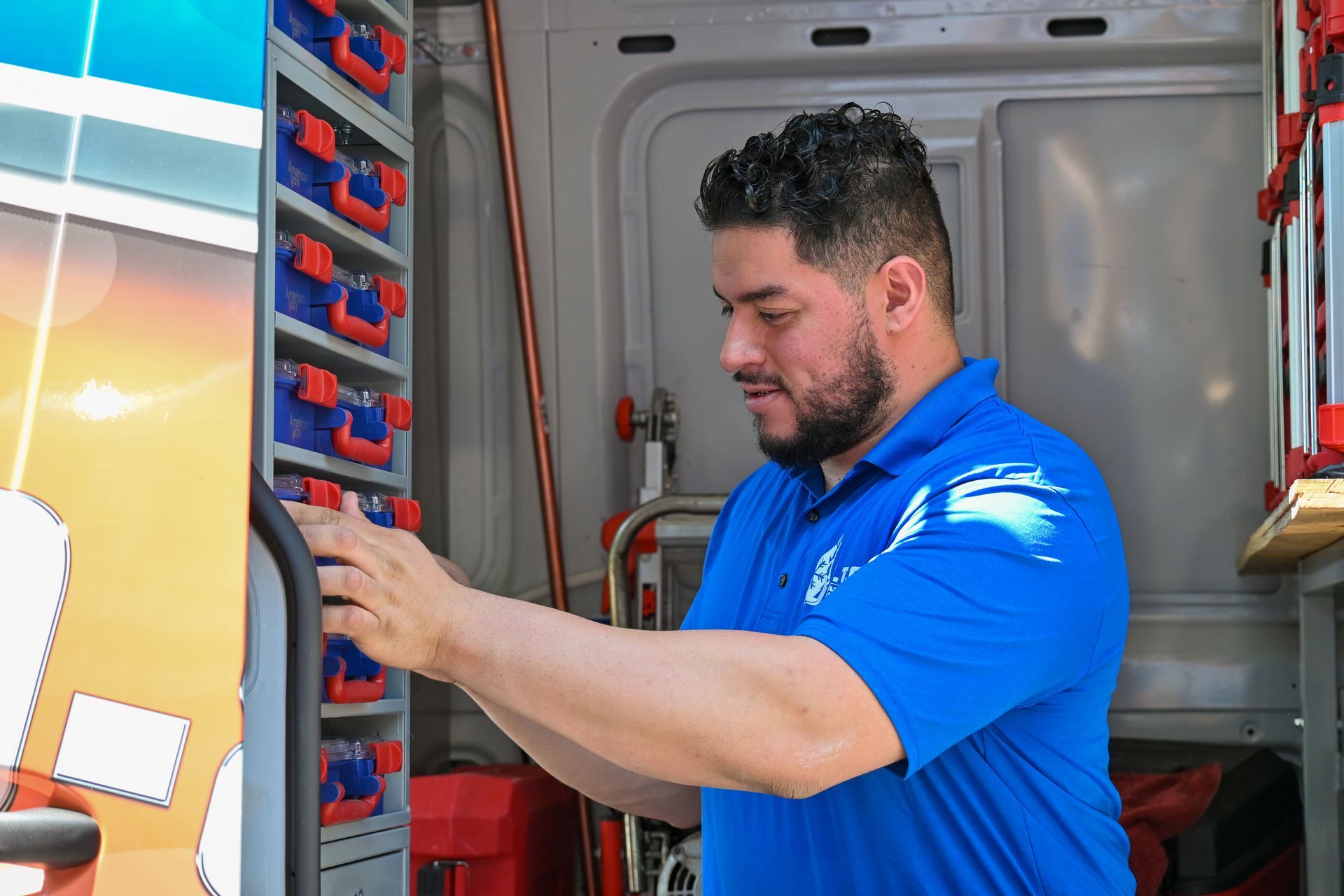 A man in a blue shirt is working in a van.