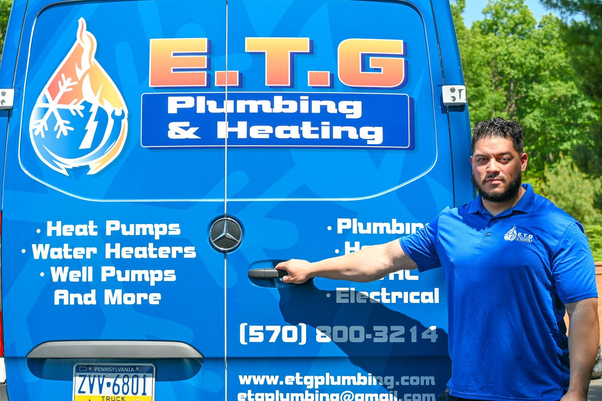 A man standing in front of a blue van that says e.t.g plumbing & heating
