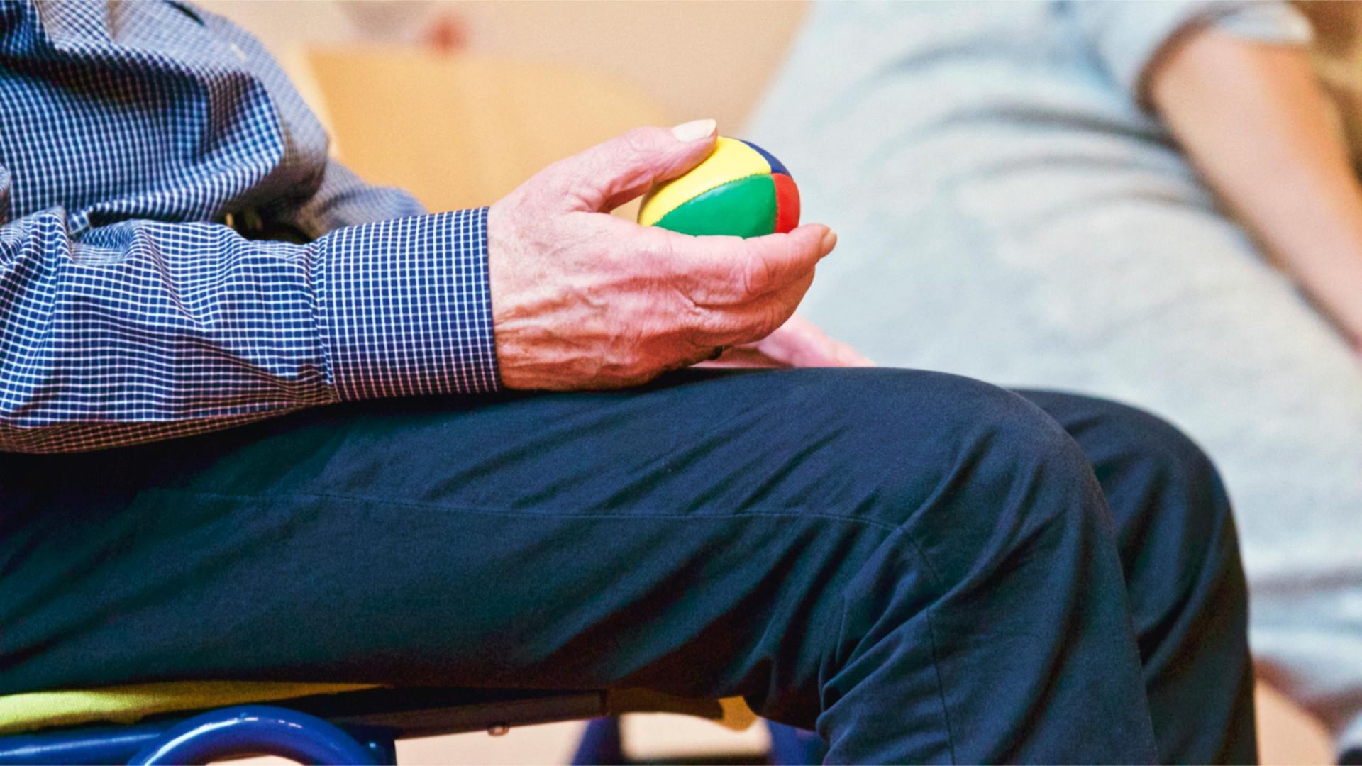 A man is sitting on a chair holding a ball in his hand.