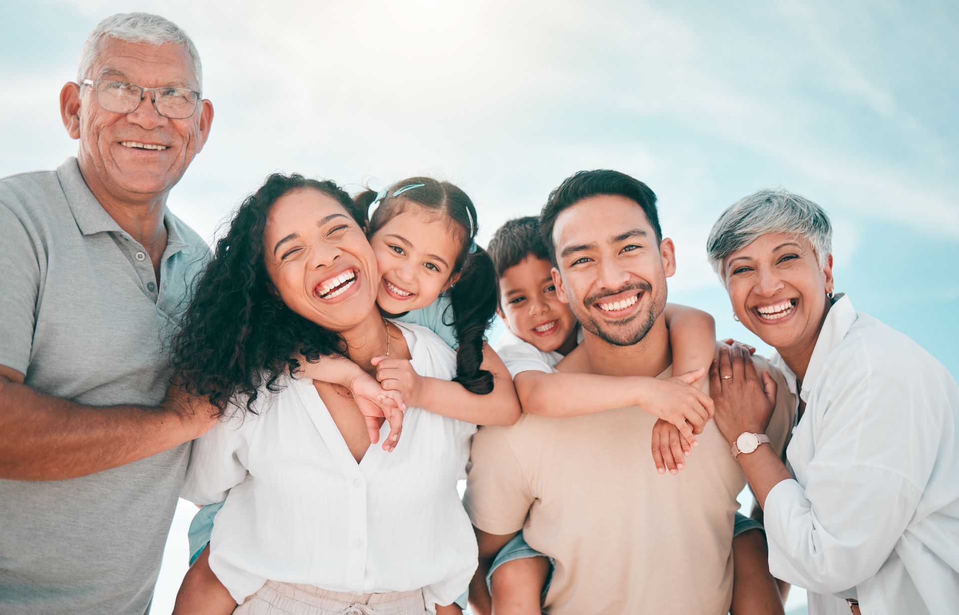 A large family is posing for a picture on the beach.