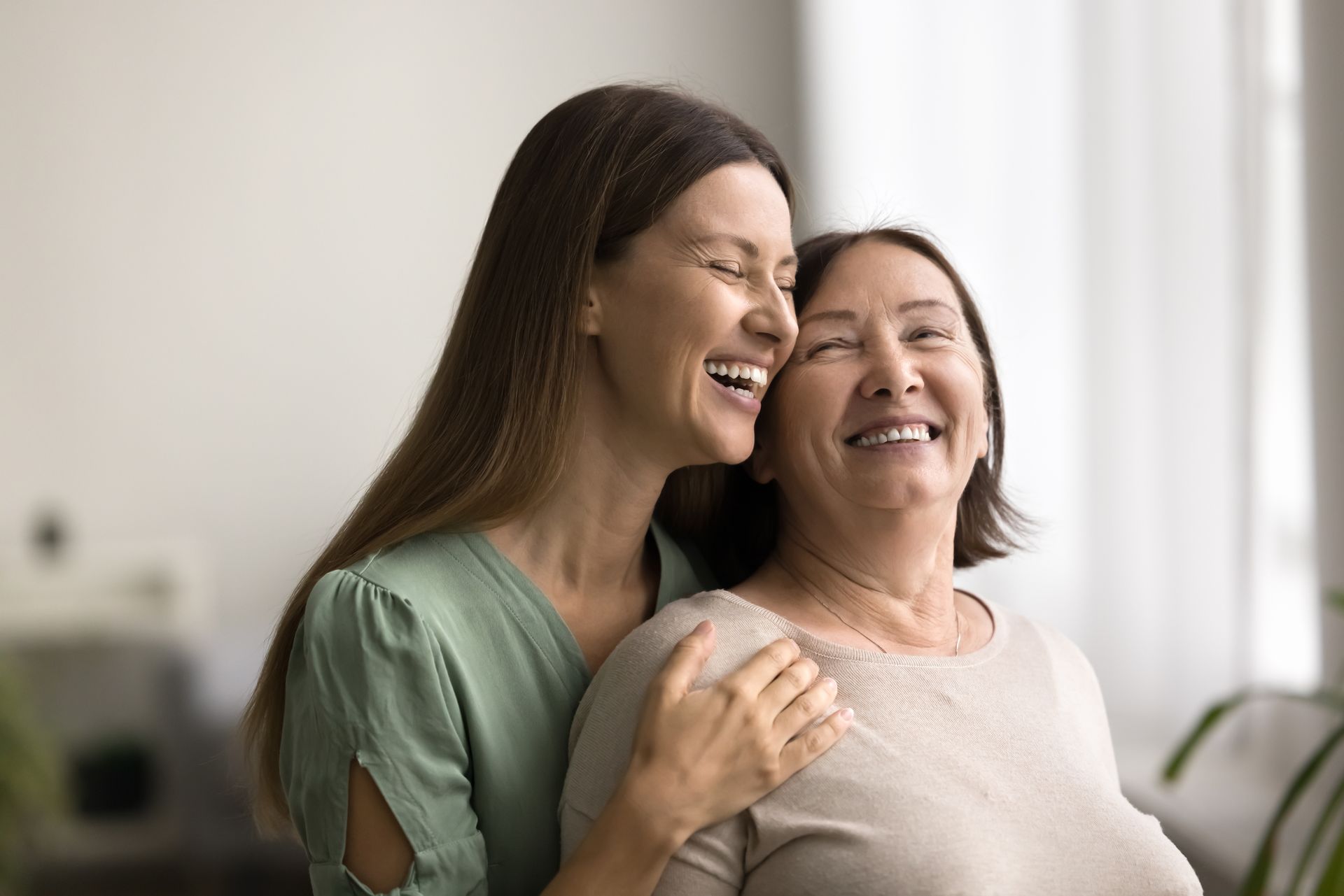 A young woman is hugging an older woman and they are smiling.
