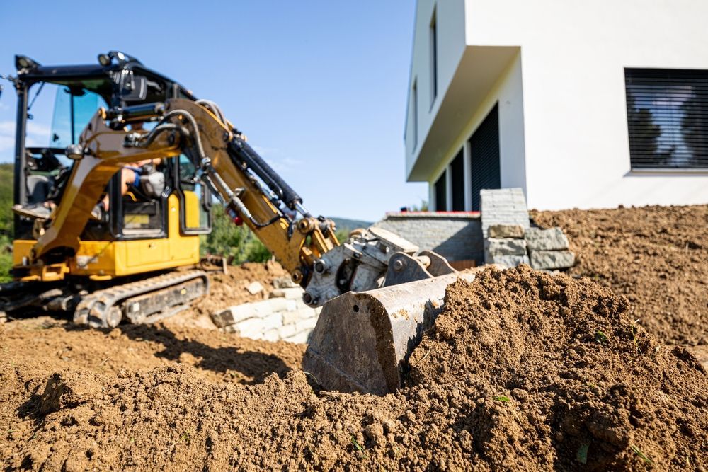 Yellow Excavator Removing Debris Near A White Building — Northern Rivers Acreage Mowing in Ballina, NSW