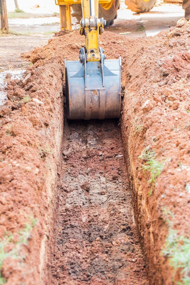 Yellow Excavator Digging A Long Trench In Red Soil — Northern Rivers Acreage Mowing in Lismore, NSW