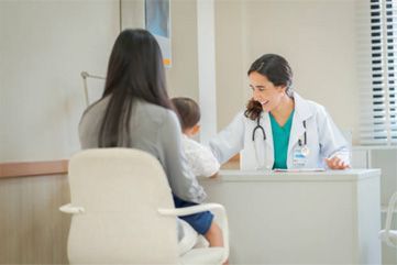 Doctor consulting with a seated patient in a bright clinic office