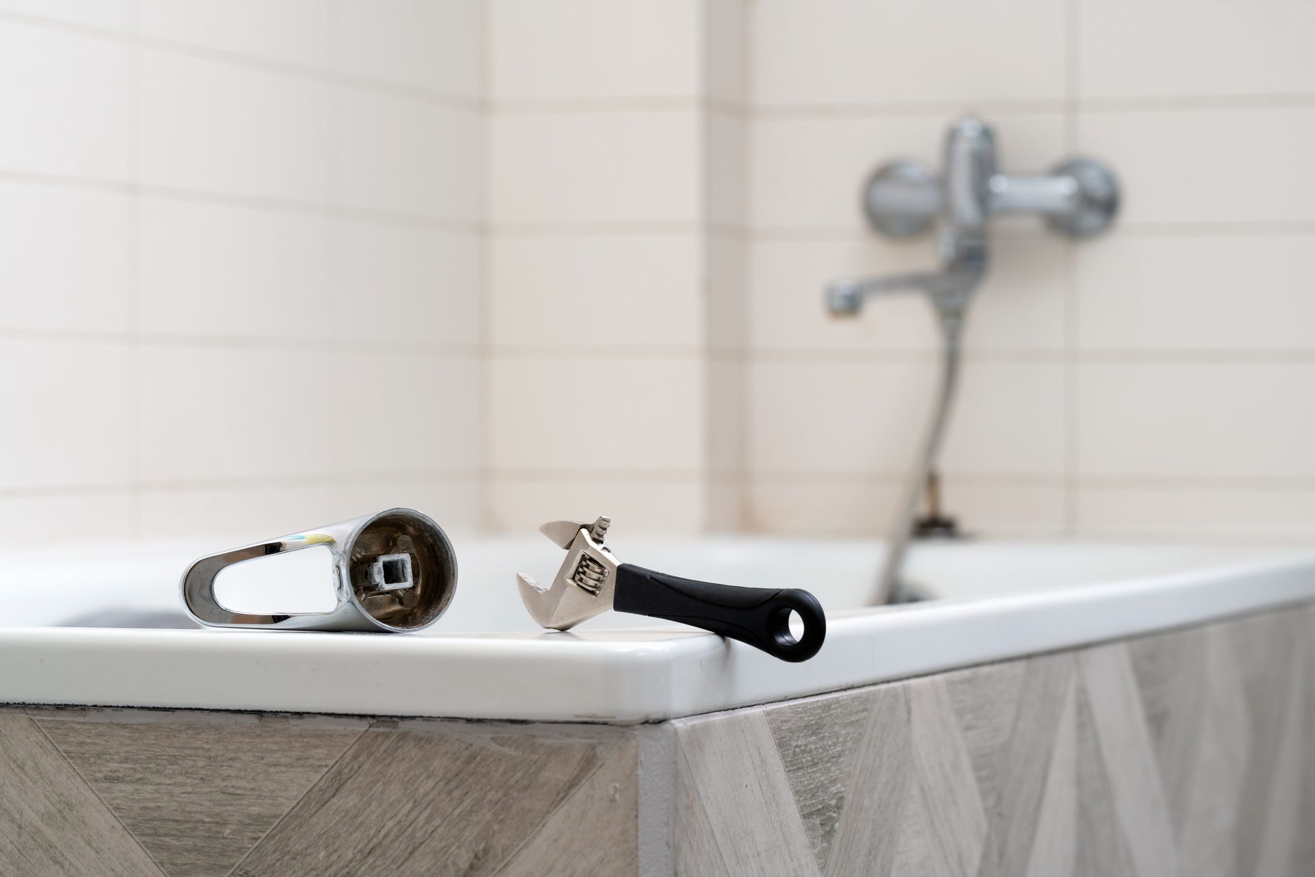 Two toothbrushes on a bathroom ledge in front of a bathtub and shower faucet.