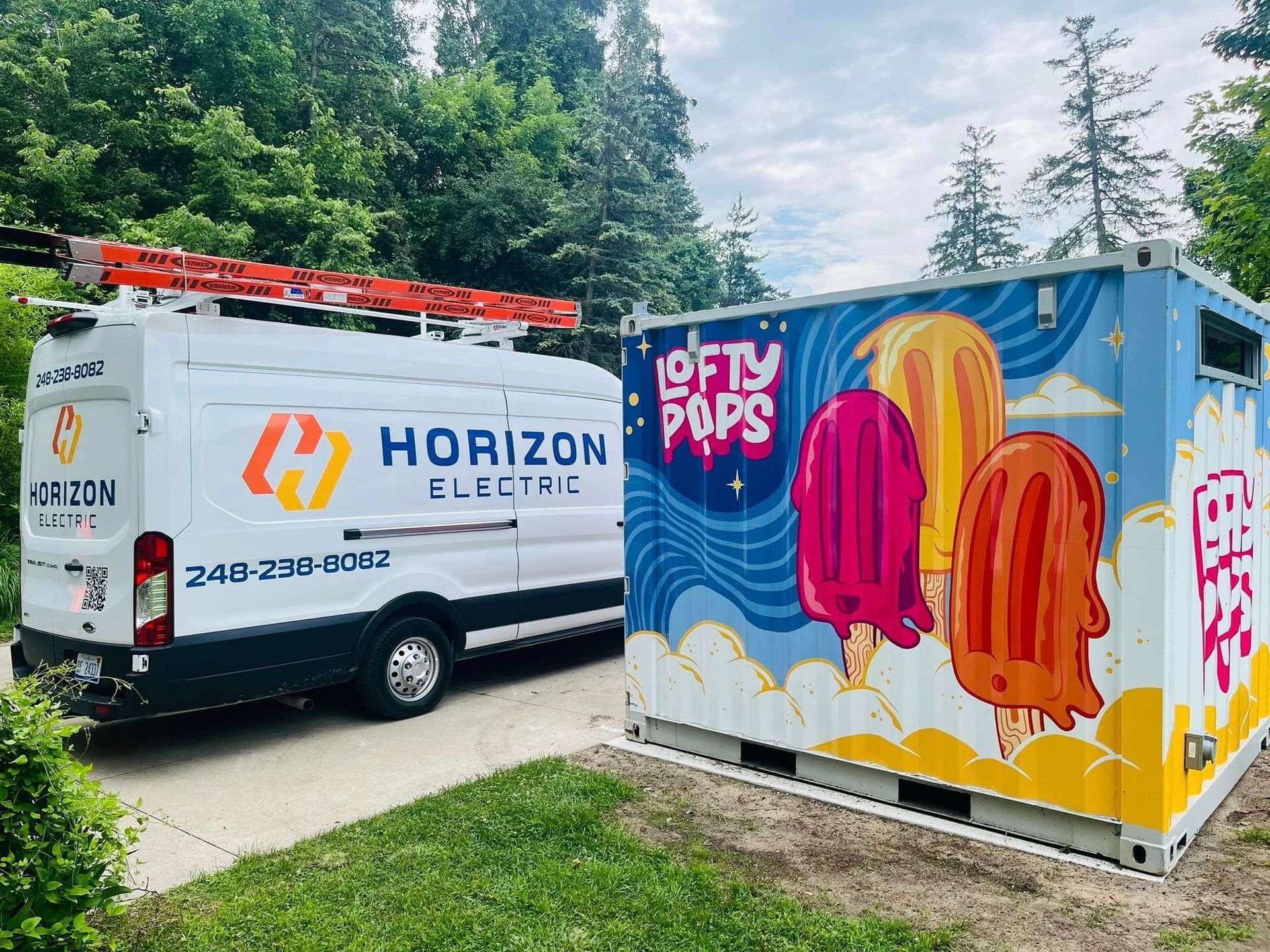 A Horizon Electric van parked next to a shipping container painted with colorful popsicles and the logo 