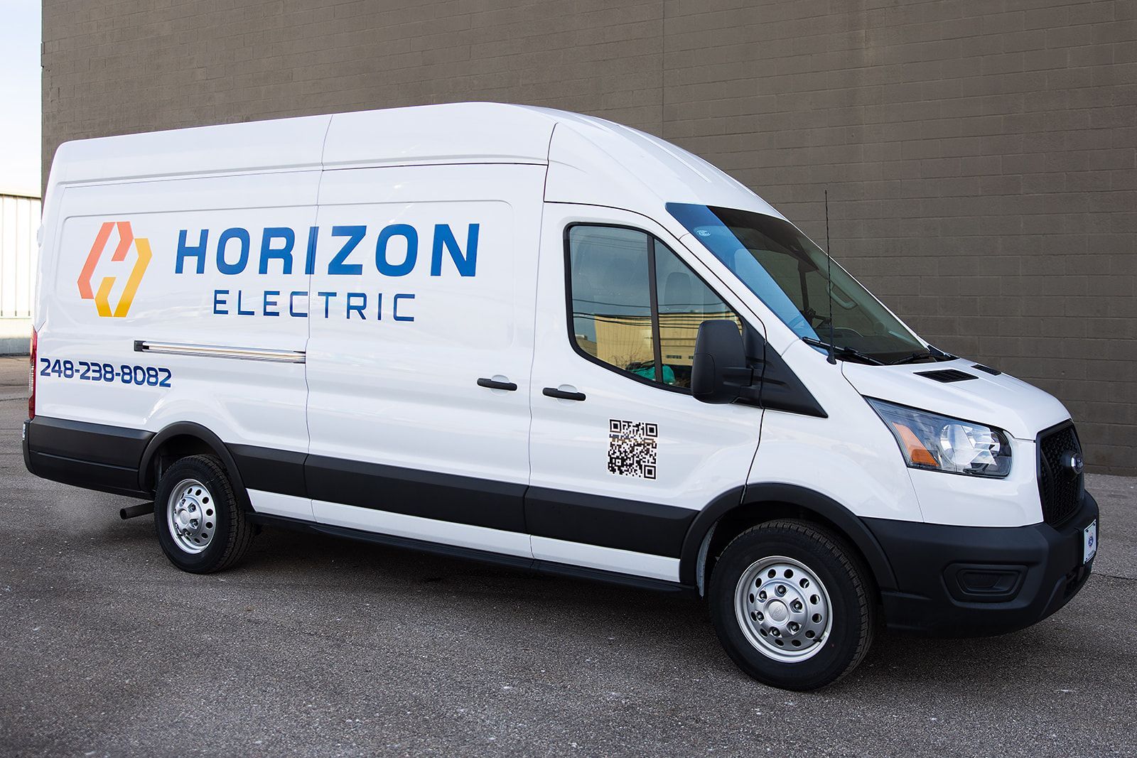 A white Horizon Electric service van parked in front of a gray brick wall.