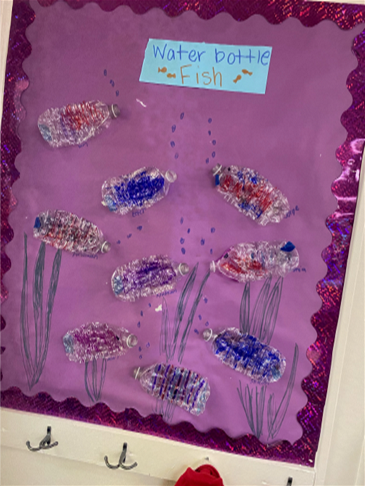 A bulletin board with a drawing of fish made out of water bottles