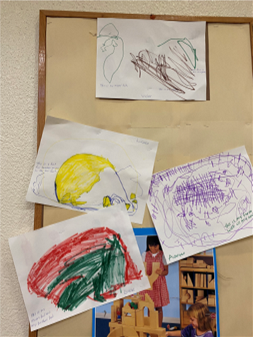 Several children 's drawings are hanging on a bulletin board