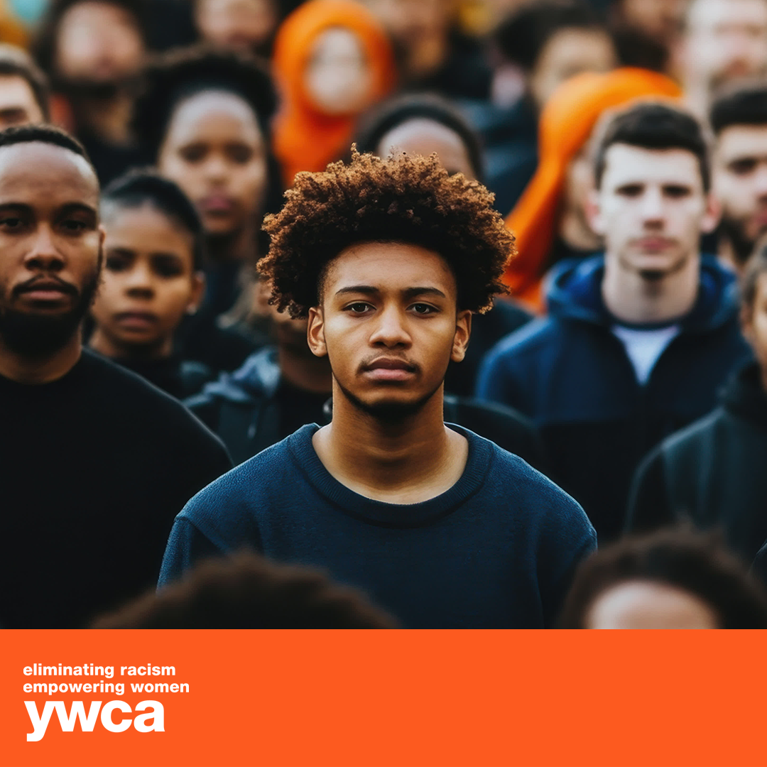 A young man stands in a crowd of people with ywca written on the bottom