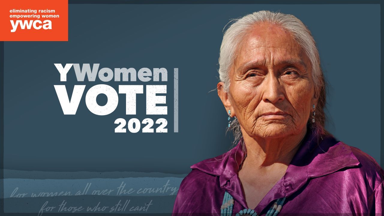 An older woman is standing in front of a sign that says ywomen vote 2022.
