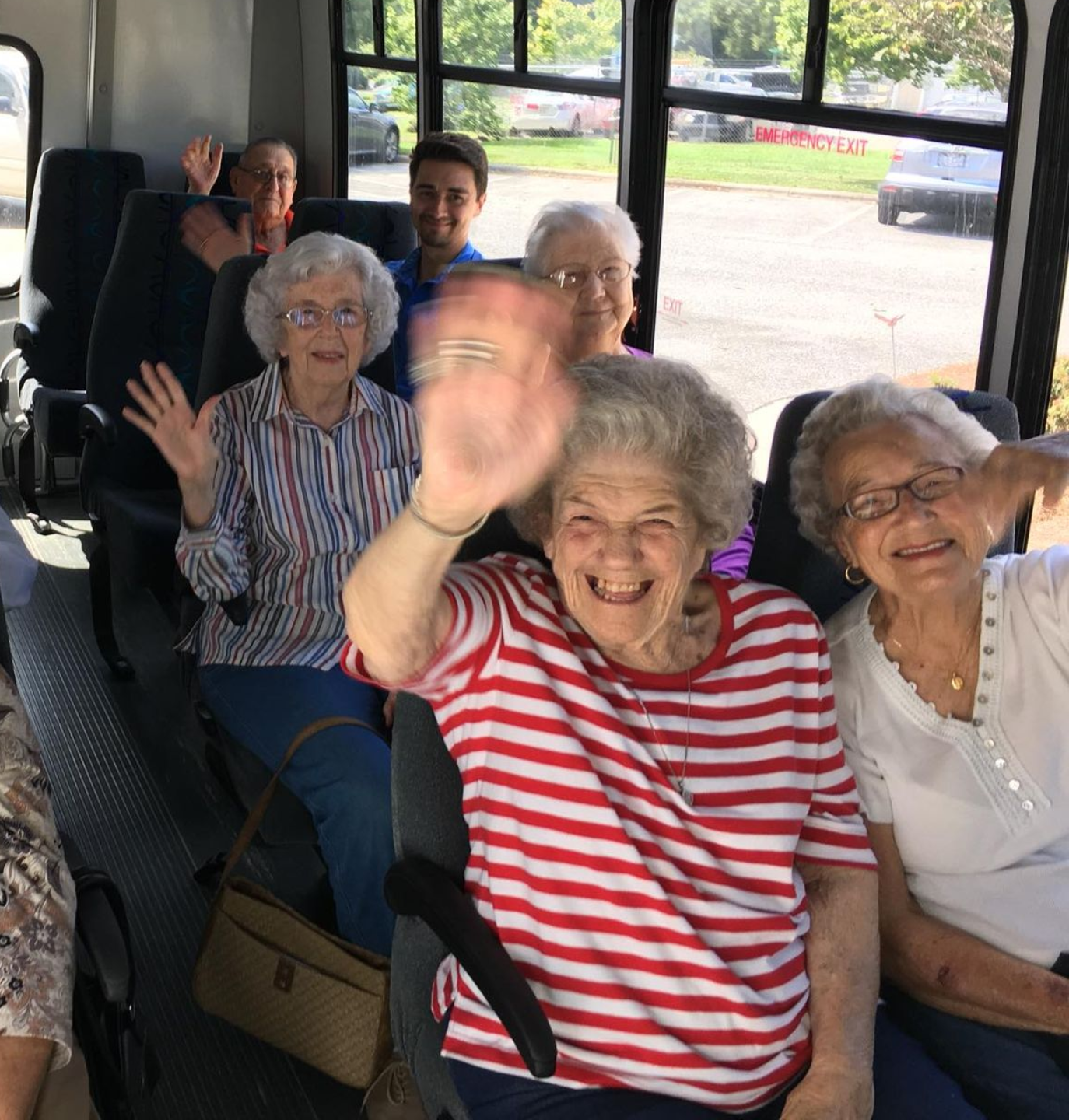 Group of people waving from inside a bus. Independent senior living community near Washington, NC.