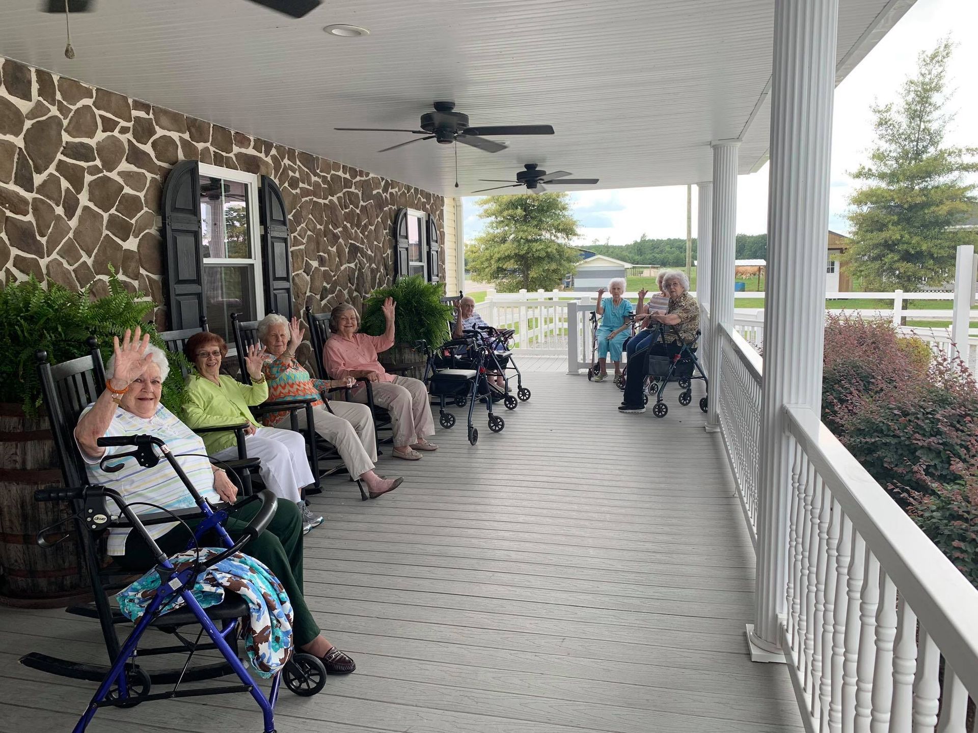 A group of elderly people are sitting on a porch.