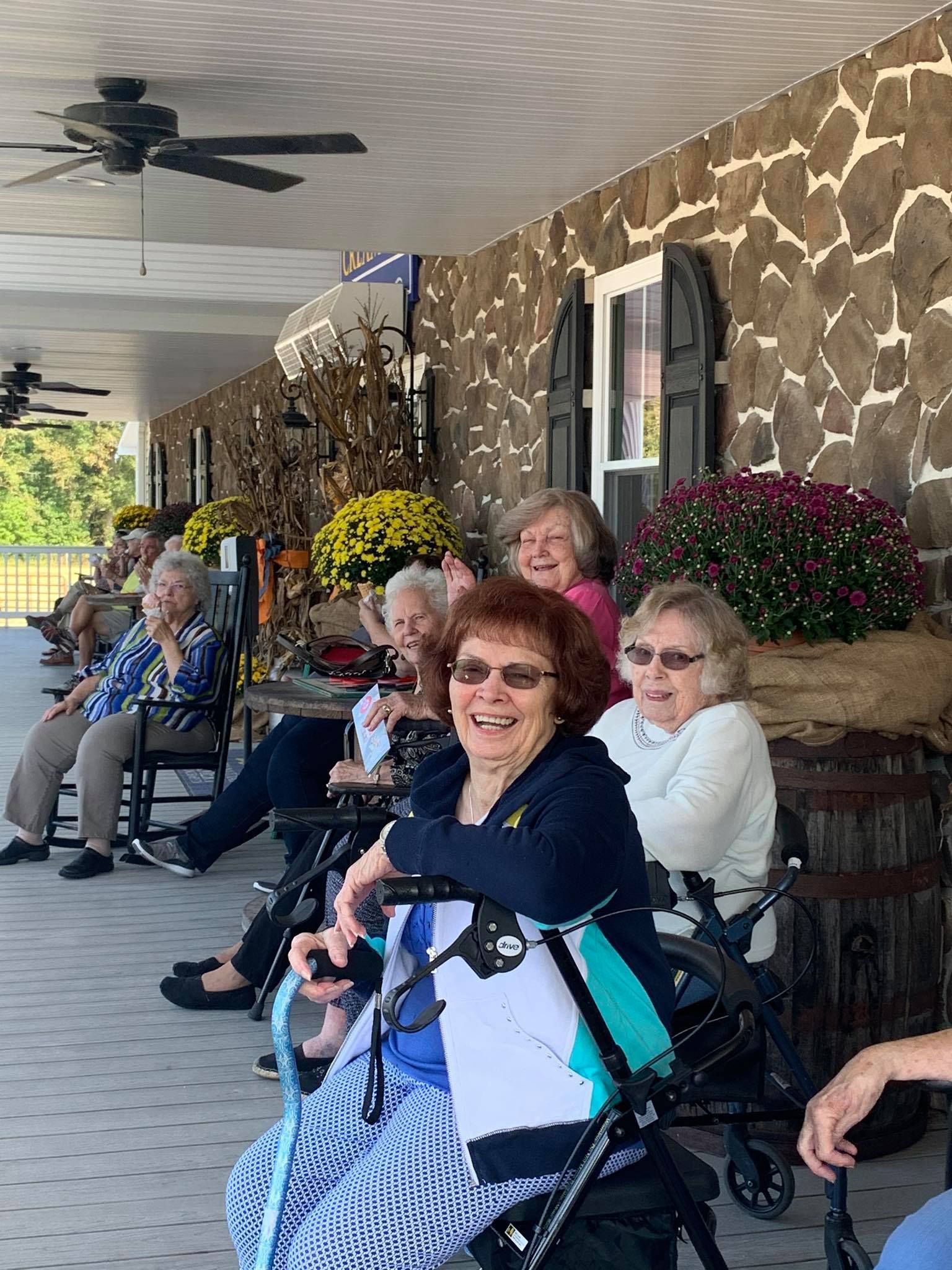 A group of elderly people are sitting on a porch.