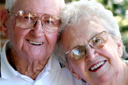 A man and a woman wearing glasses are smiling for the camera.