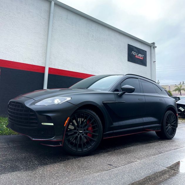 A black car is parked in front of a building.
