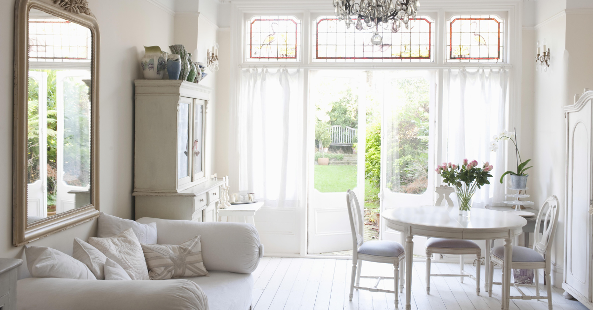 A living room with a white couch , table and chairs.