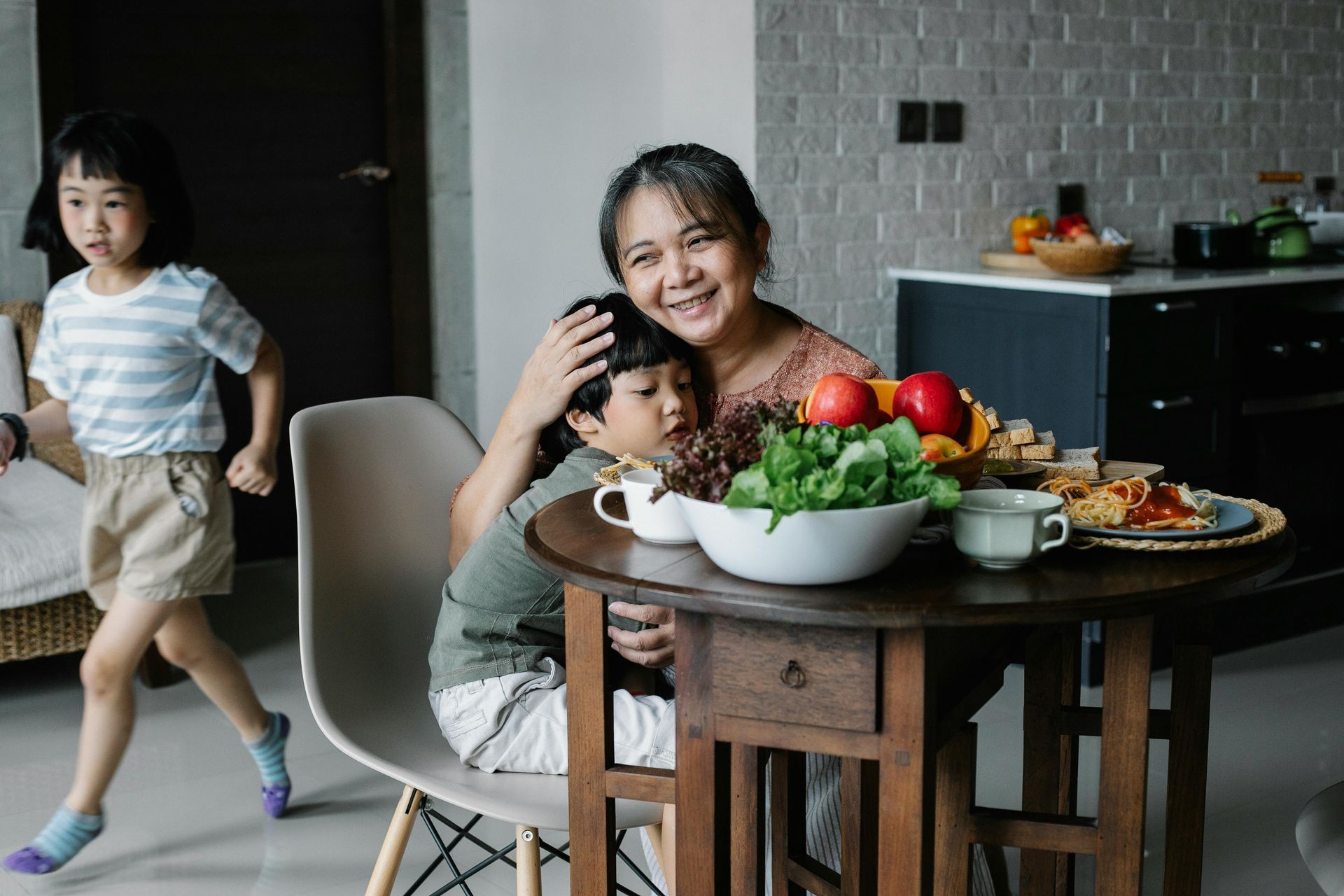 A woman is sitting at a table with a child on her lap.
