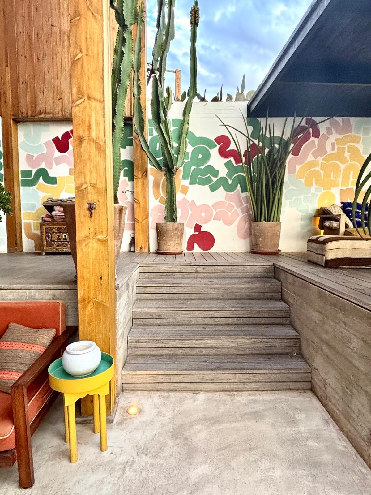 Photo taken by K Interiors in Morocco. Featuring steps, a glimpse of an outdoor seating area, a mural and a yellow table.
