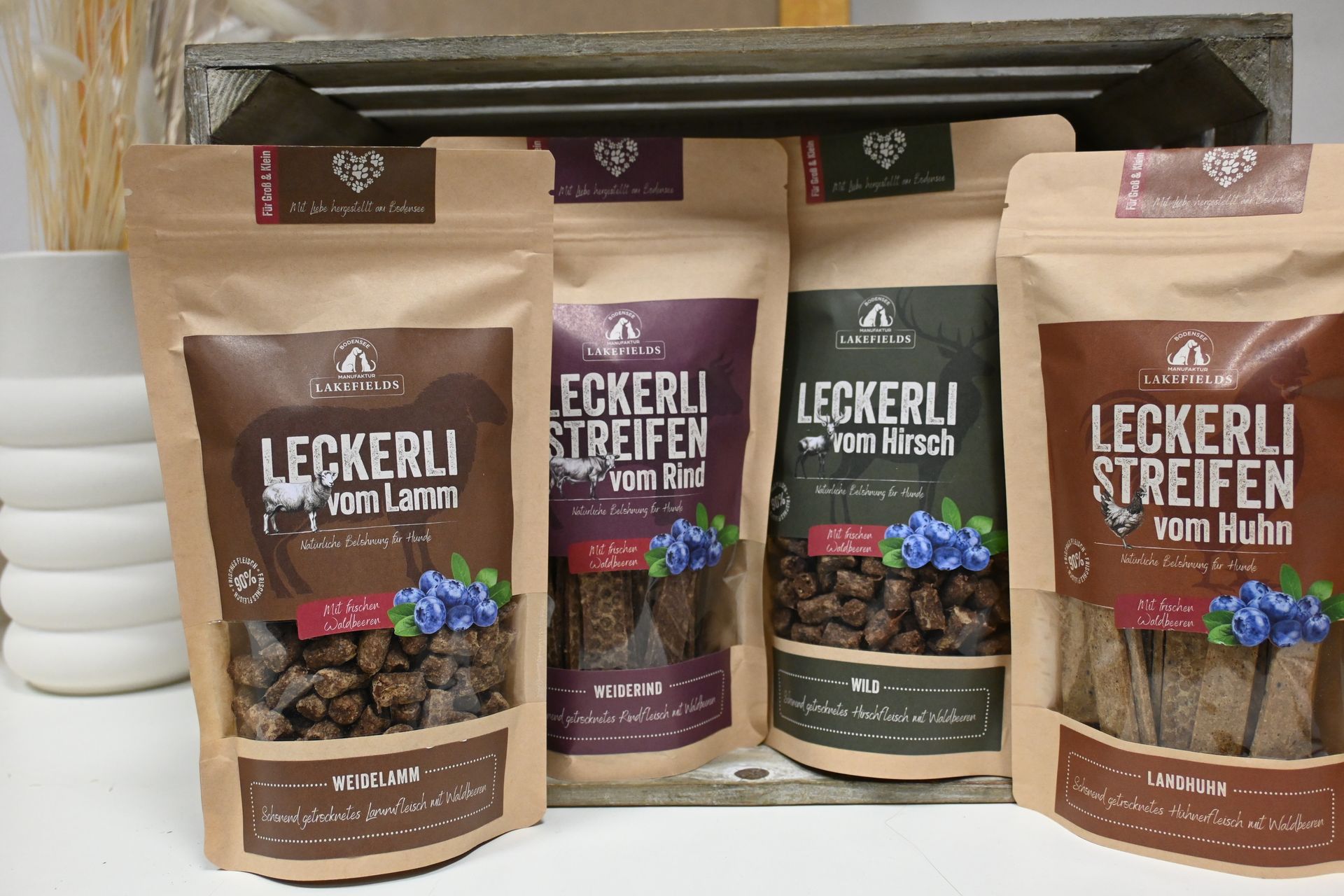 Verschiedene Leckerli-Hundeleckerli-Beutel auf einem Regal, Beeren- und Hühnergeschmack sind sichtbar.