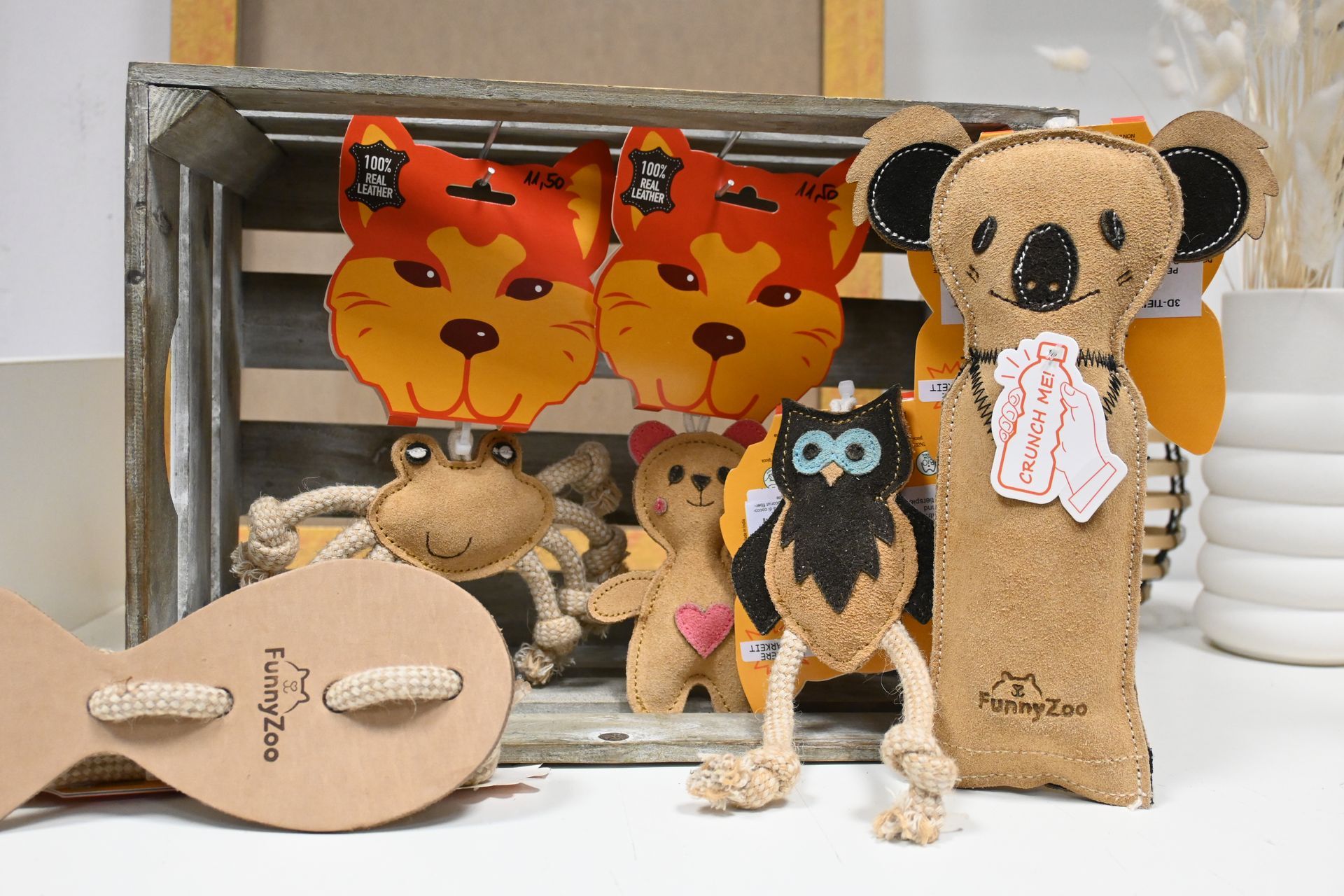 Handgefertigte Plüschkoalas, Eulen und Bären, ausgestellt auf einem weißen Regal mit bunten Blattdekorationen.