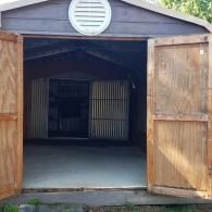 Open wooden shed with double doors ajar and a concrete floor inside