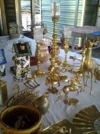 Assorted gold decorative candlesticks and figurines arranged on a table by a window